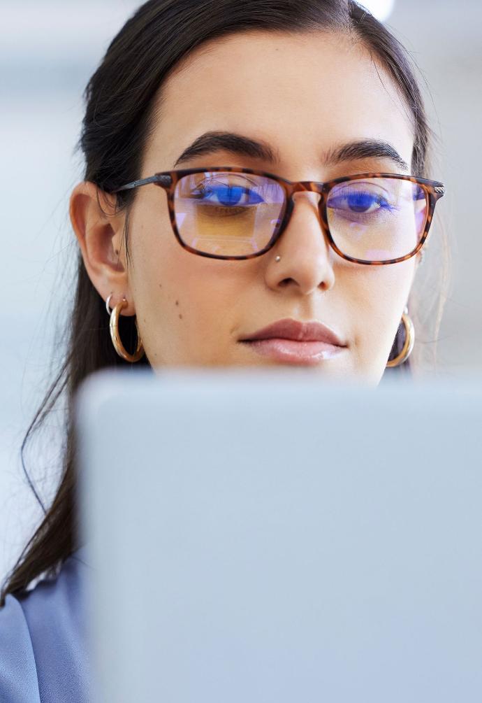 Frau mit Brille, die auf einen Bildschirm schaut