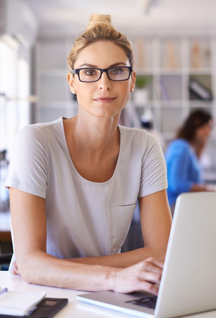 Frau mit Brille im Büro, die in die Kamera schaut