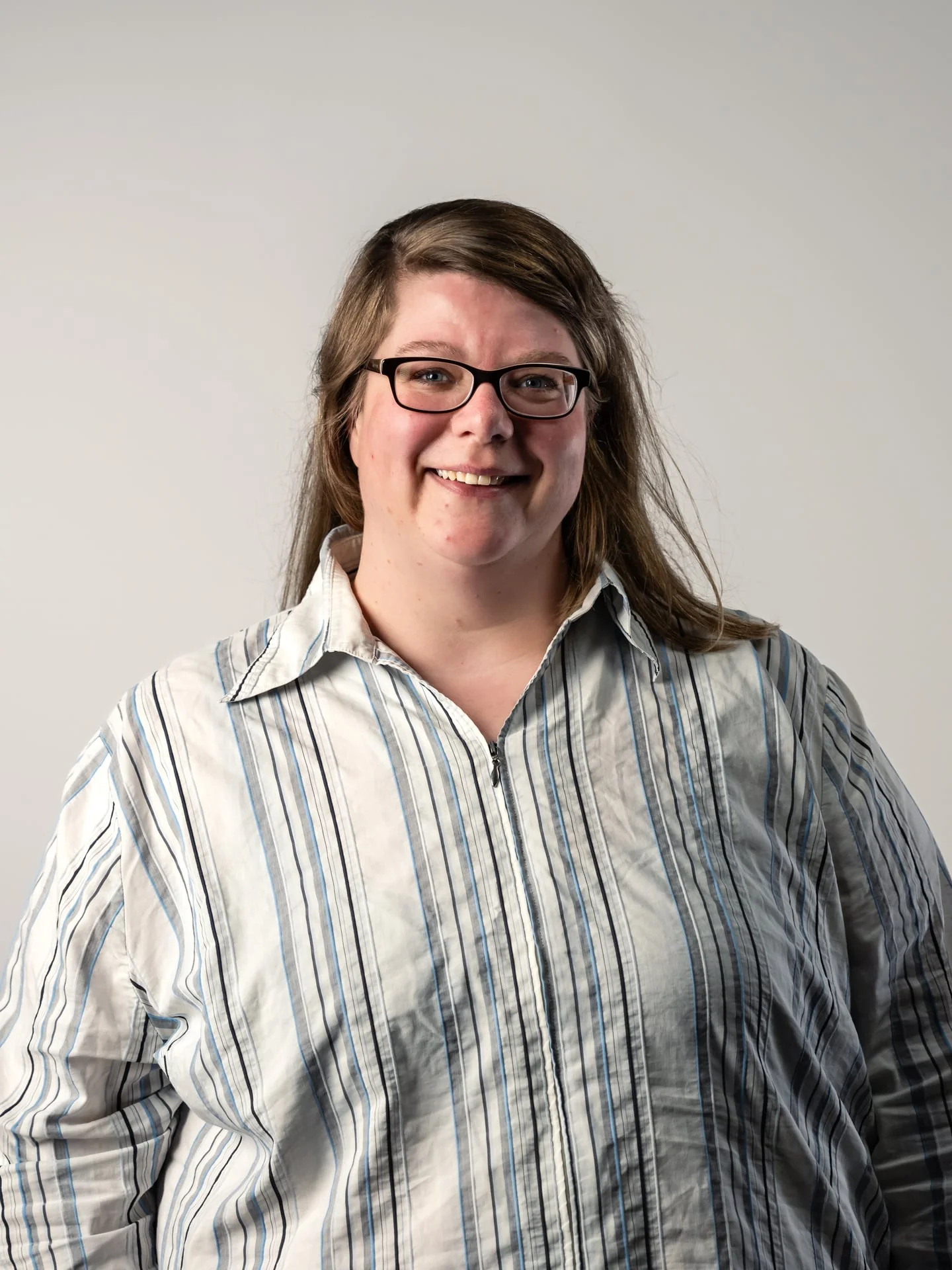 Elke Heermann, Hotline bei medacom, lächelnde Frau mit Brille und gestreifter Bluse vor hellem Hintergrund