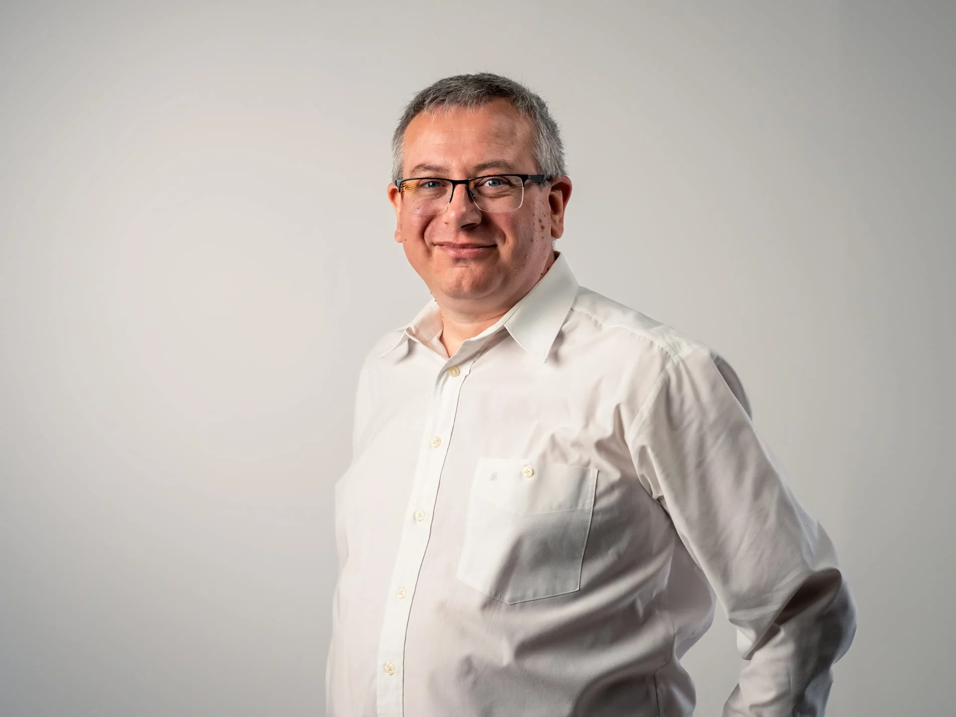 Holger Kuhrt, Support & Technik bei medacom, lächelnder Mann mit Brille und grauen Haaren in weißem Hemd