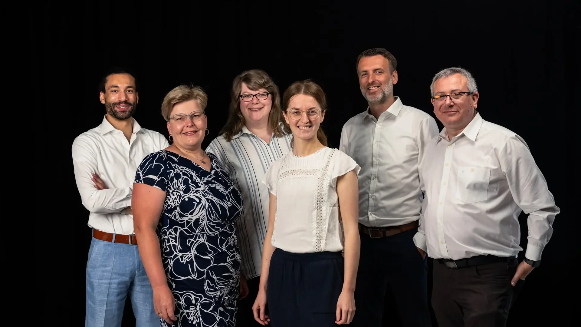 Sechs Personen des medacom-Teams im Gruppenporträt vor schwarzem Hintergrund